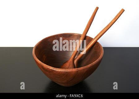 Kitchen utensils: empty wooden bowl with spoon and fork on black desk Stock Photo