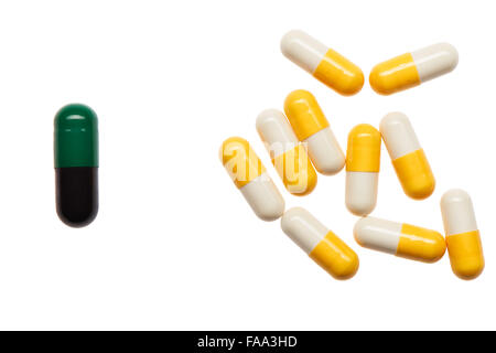 Pile of yellow and white capsules and one bigger green and black capsule isolated on white background. Clipping path included. Stock Photo
