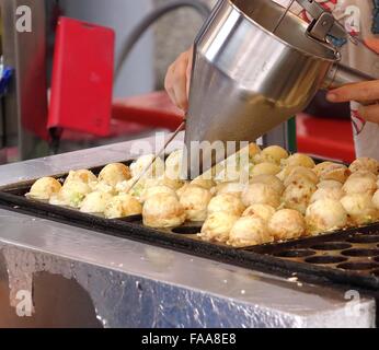 A street vendor makes balls filled with octopus meat and cabbage Stock Photo