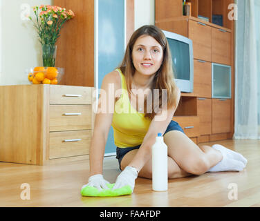 housewife rubing parquet floor with furniture polish at home Stock Photo