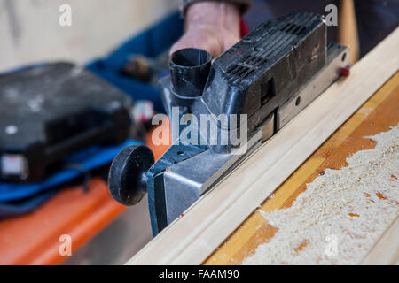 Carpenter working with doorjambs using electric jack plane Stock Photo