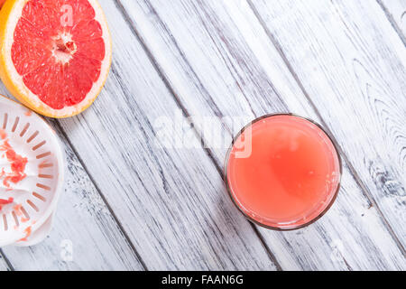 Pure Grapefruit Juice (close-up shot) on rustic wooden background Stock Photo