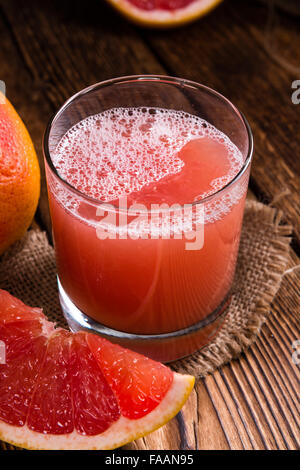 Glass with Grapefruit Juice (close-up shot) on wooden background Stock Photo