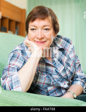 Stressed female pensioner laying on her elbows and thinking  on couch Stock Photo