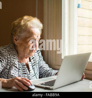 An elderly woman works on a laptop. Stock Photo