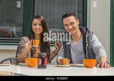 A couple is sitting on the terrace and having breakfast Stock Photo