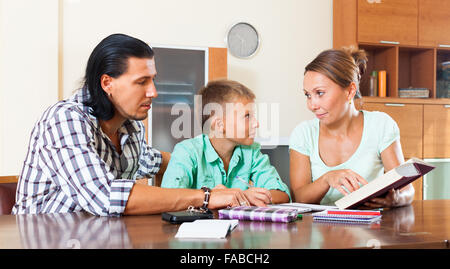 Smiling schoolboy doing homework with parents Stock Photo