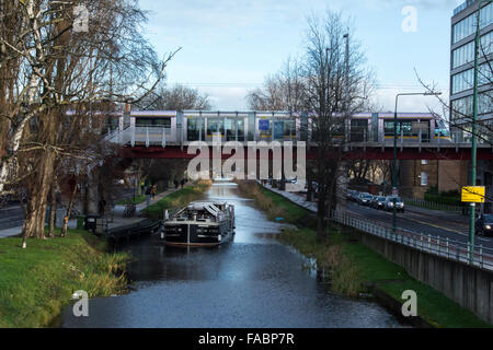 The Grand Canal in central Dublin with a barge and the Luas LRT on a bridge Stock Photo