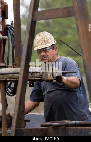Oil workers sink pipe using a derrick to drill for crude in Evangeline, Louisiana. The oil fields were the first wells in Louisiana. Stock Photo