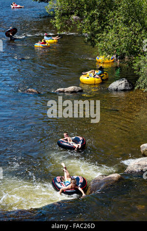 People raft using tubes down the Yampa River on a summer day in Steamboat Springs, Colorado. Stock Photo