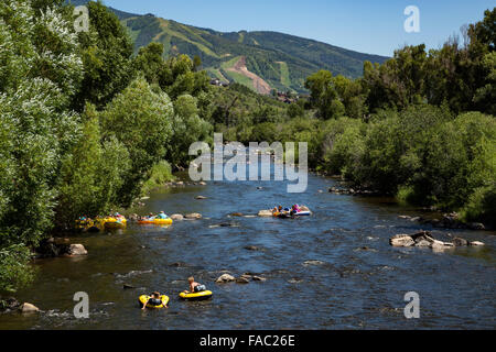 People raft using tubes down the Yampa River on a summer day in Steamboat Springs, Colorado. Stock Photo