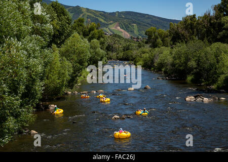 People raft using tubes down the Yampa River on a summer day in Steamboat Springs, Colorado. Stock Photo