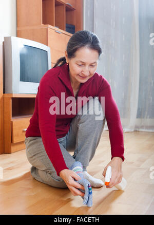 mature housewife polishing parquet floor with  polish Stock Photo