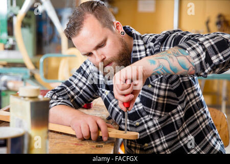 Craftsman files wooden guitar neck in workshop Stock Photo