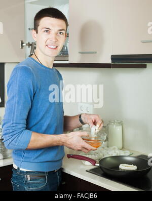 Handsome guy cooking frying squid rings in batter at kitchen Stock Photo