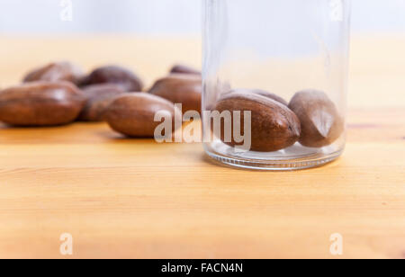Pecan walnuts on glass jar over wooden surface. Isolated over white background Stock Photo