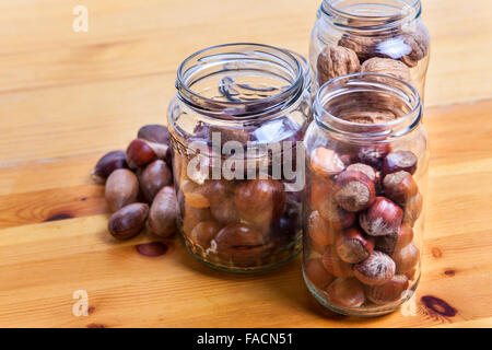 Nuts on glass jars over wooden surface. Isolated over white background Stock Photo