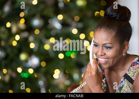 US First Lady Michelle Obama smiles while talking on the phone to children across the country as part of the annual NORAD Tracks Santa program on Christmas Eve December 24, 2015 in Kailua, Hawaii. Stock Photo