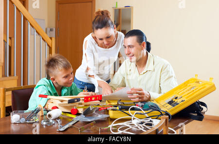 Father and son are doing with their hands crafts in home, woman helps them at home Stock Photo