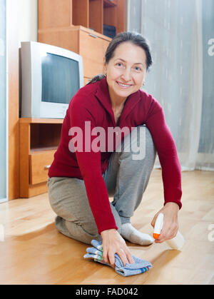 woman rubing  floor with furniture polish at home Stock Photo