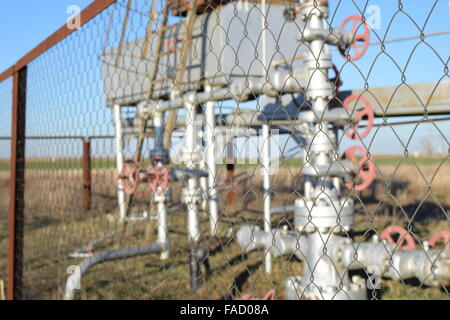 Grid the chain-link near an oil well. Shutoff valves and service equipment. Stock Photo