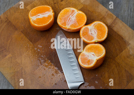 juicy clementines cut in half on a wooden chopping board Stock Photo