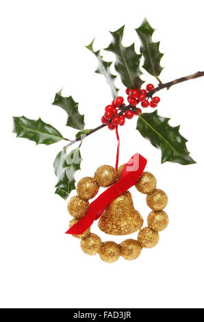 Bell and ball gold glitter Christmas decoration hanging in a holly branch Stock Photo