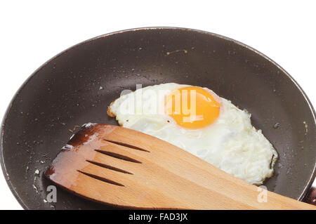 Closeup of a fried egg with a wooden spatula in a frying pan Stock Photo