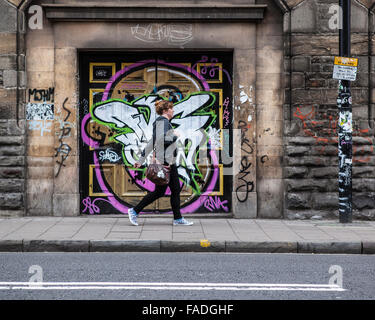 Woman walking past street art graffiti in Bristol