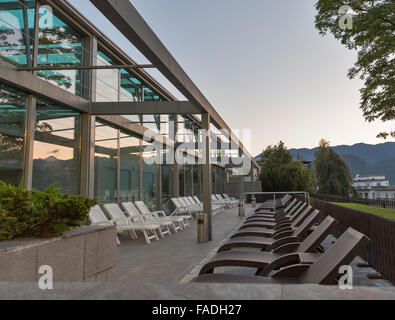 Sunset terrace with sunbeds in a rows near the outdoor swimming pool at the recreation center Stock Photo