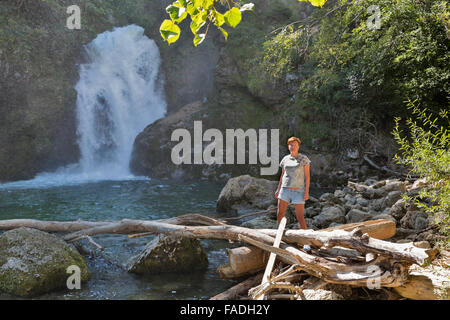 Middle aged tanned Caucasian woman stands in front of waterfall Sum. Vintgar gorge, Triglav national park in Slovenia Stock Photo