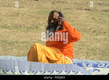 Allahabad, Uttar Pradesh, India. 28th Dec, 2015. India, Uttar Pradesh, Allahabad: A sadhu talk on mobile after arrive to attend Magh mela fair at bank of Sangam, the confluence of River Ganga Yamuna and mythological saraswati in Allahabad on 28 December, 2015. The Magh Mela is held every year on the banks of Triveni Sangam - the confluence of the three great rivers Ganga, Yamuna and the mystical Saraswati during the Hindu month of Magh which corresponds to mid January - mid February. © Prabhat Kumar Verma/ZUMA Wire/Alamy Live News Stock Photo