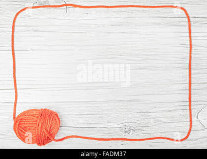 Red frame made of yarn on wooden board, background with space for text. Stock Photo