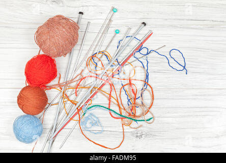Tangled threads with yarn balls and needles on wooden board, concept background with space for text. Stock Photo