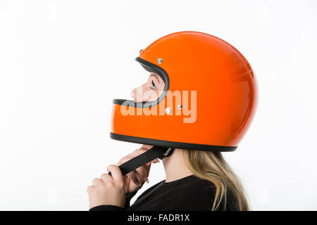 Cute girl with blond hair with orange motorcycle helmet. Studio shot on white background. Stock Photo