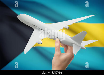 Airplane in hand with national flag on background - Bahamas Stock Photo