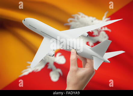Airplane in hand with national flag on background - Bhutan Stock Photo