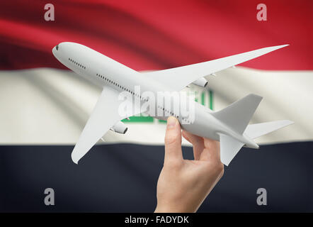 Airplane in hand with national flag on background - Iraq Stock Photo