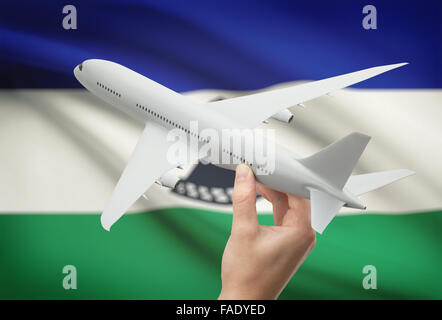 Airplane in hand with national flag on background - Lesotho Stock Photo