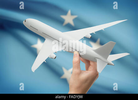 Airplane in hand with national flag on background - Micronesia Stock Photo