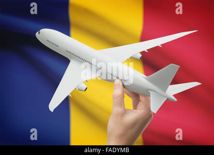 Airplane in hand with national flag on background - Romania Stock Photo
