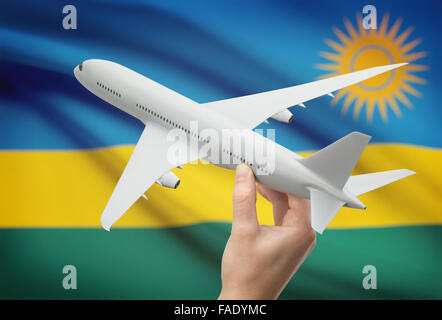 Airplane in hand with national flag on background - Rwanda Stock Photo