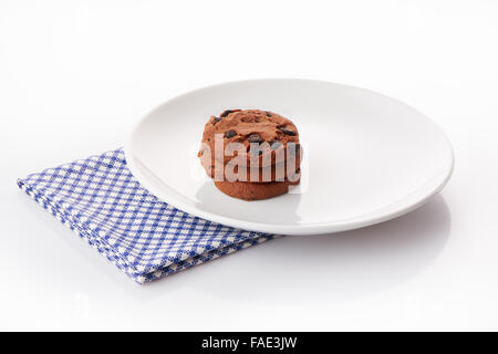 Stack of three homemade chocolate chip cookies on white ceramic plate on blue napkin, isolated on white background Stock Photo