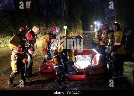 York, UK. 28th December, 2015. Fifteen Fire Fighters from the West Midlands and Northampton Fire and Rescue Services spent four hours in pitch dark last Night to rescue the woman who was stranded at a stables. Crews where called out  to the remote riding stables  just after 4.30. The dramatic footage show the woman in a basket Stretcher being upload from one of specialist rescue team rubber boat.The crews had to  walk in moving flood water shoulder deep in some parts  to rescue the medically sick woman who had been cut off by Flooding in York. Credit:  uknip/Alamy Live News Stock Photo