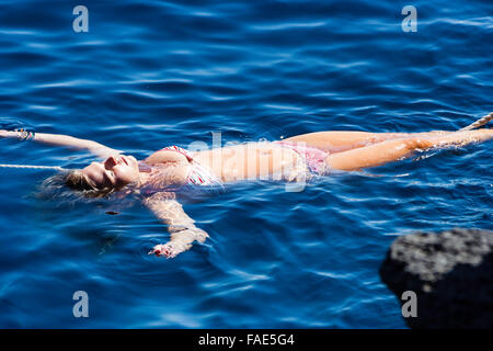 portrait of teenage girl in bikini sitting in the water Stock