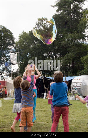 CHEPSTOW, WALES - July 2014: Children attempt to pop a giant soap bubble on 31 July at the Green Gathering Festival Stock Photo