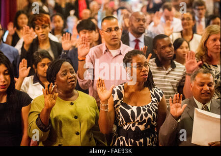 People raising their hand to give an oath during a naturalization ceremony becoming US citizens. Stock Photo