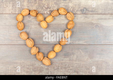 Heart made of walnuts on wooden background, space for text. Stock Photo