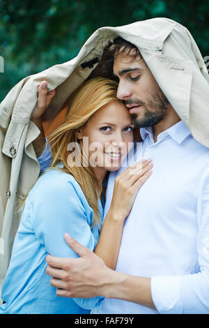 Affectionate young couple standing under coat Stock Photo