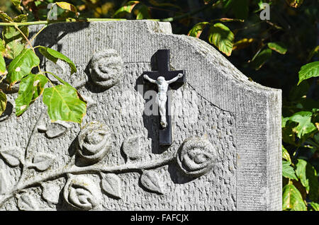 Cross and flower on the tombstone in the public cemetery Stock Photo